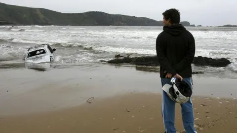 Un coche arrastrado hasta la playa de Verdicio, en Asturias