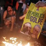 Seguidores del Partido de los Trabajadores queman un cartel con las fotos del nuevo presidente, Michel Temer, y del presidente del Senado