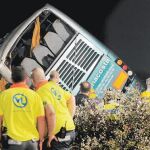 Bomberos y personal de los equipos de emergencias sanitarias observan el autocar, volcado, tras el grave accidente