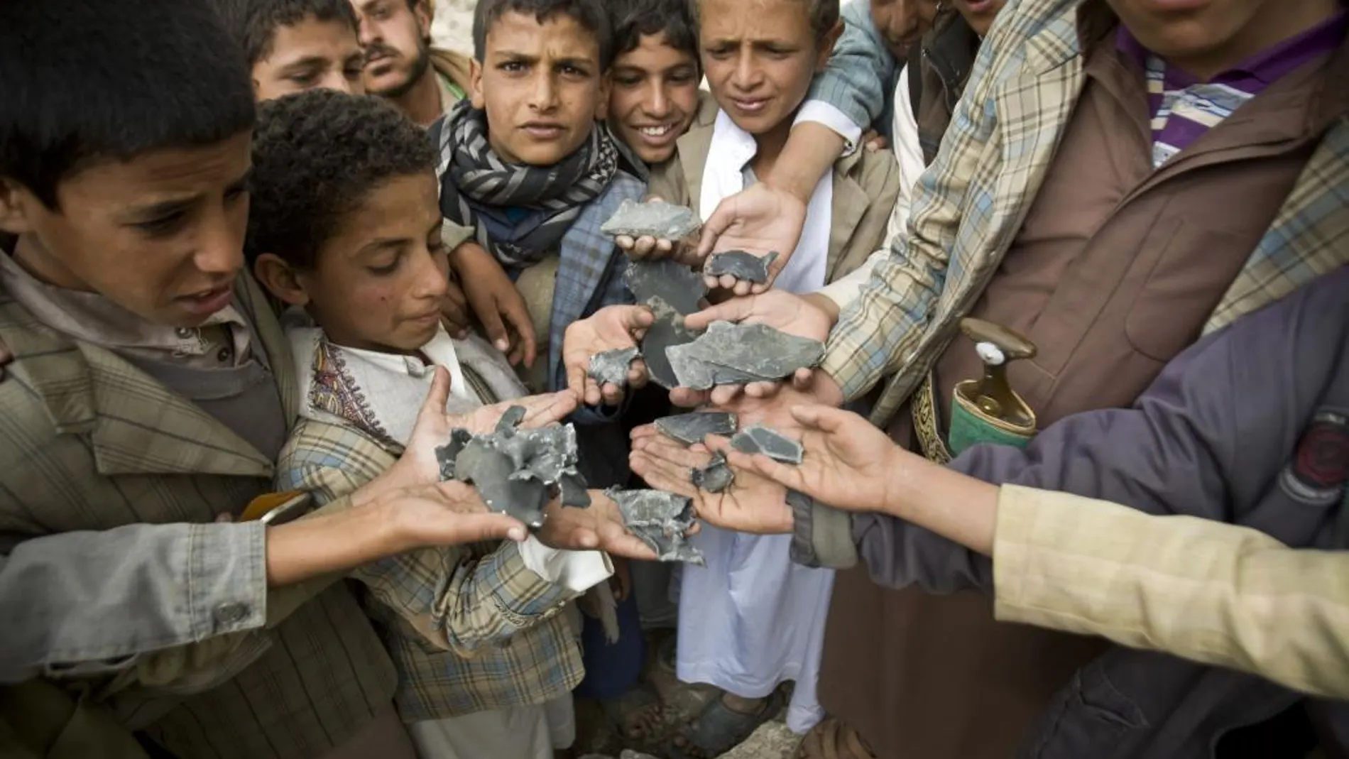 Niños yemeníes muestran metralla recogida entre los escombros de sus casas