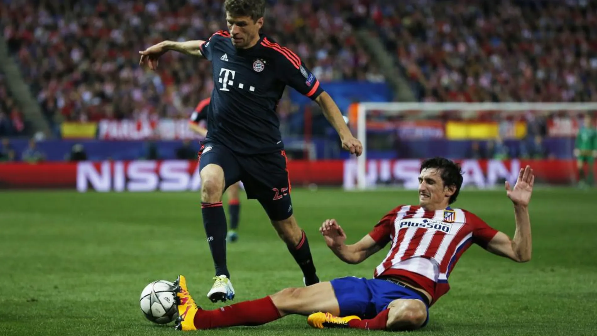 El defensa montenegrino del Atlético de Madrid Stefan Savic (d) lucha el balón con Thomas Muller, del Bayern de Múnich