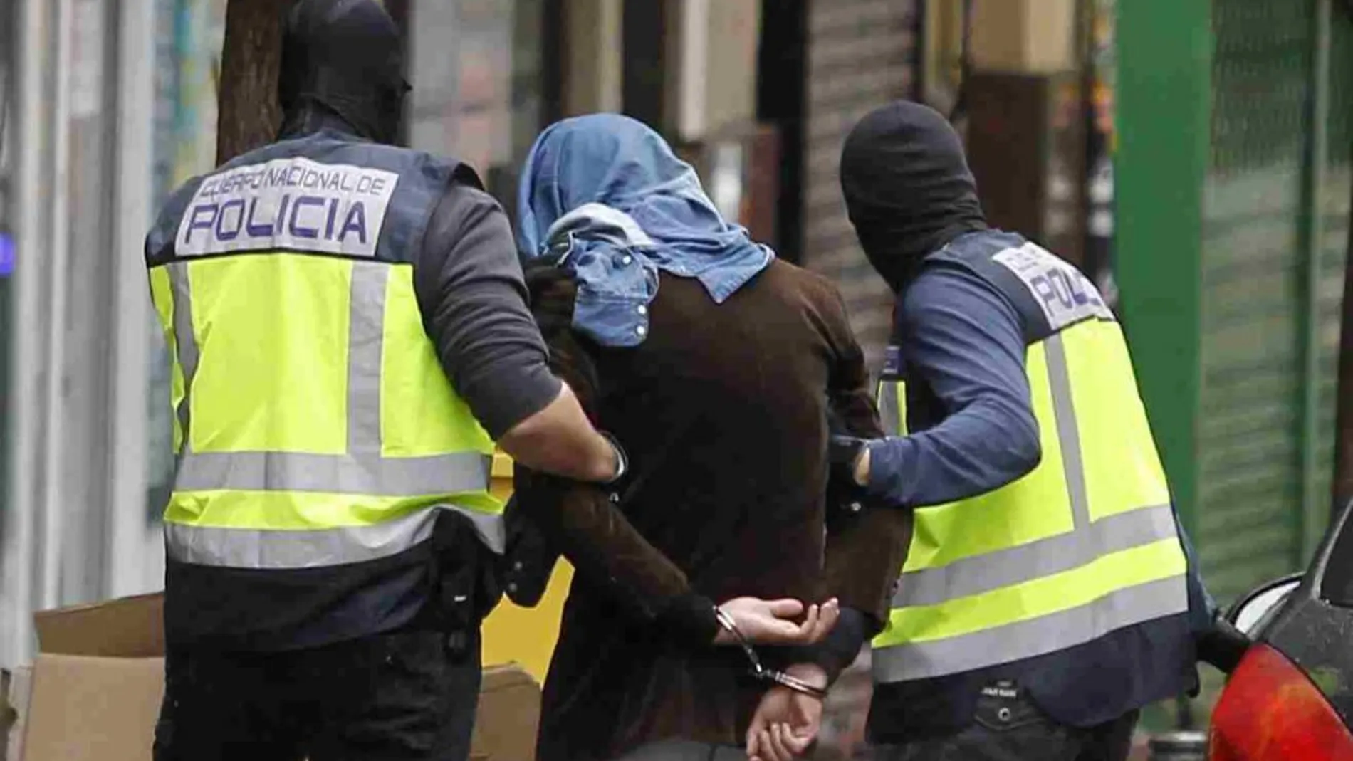 Dos policías acompañan a un presunto yihadista detenido en Madrid, acusado de formar parte de un grupo vinculado al Estado Islámico.