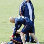 Iniesta hace ejercicios sobre el césped con la ayuda de uno de los recuperadores de la selección ante la presencia de Del Bosque