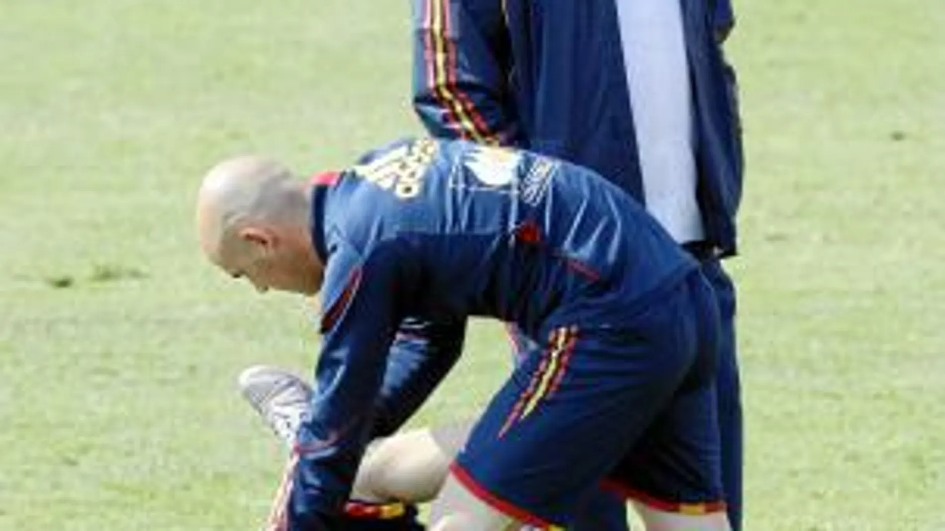 Iniesta hace ejercicios sobre el césped con la ayuda de uno de los recuperadores de la selección ante la presencia de Del Bosque