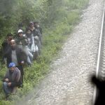 Un grupo de inmigrantes camina junto al lugar donde se produjo la muerte de otros 14 inmigrantes al ser arrollados por un tren