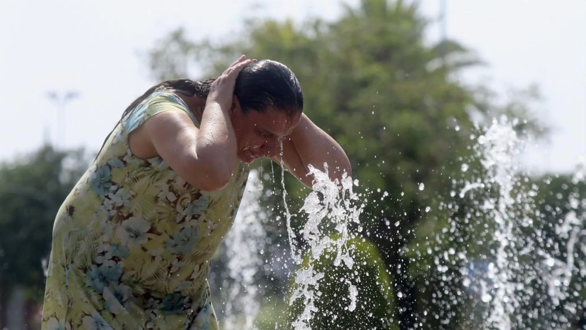 Una mujer se refresca en una de las fuentes de la ciudad debido a las altas temperaturas que se registran en Córdoba
