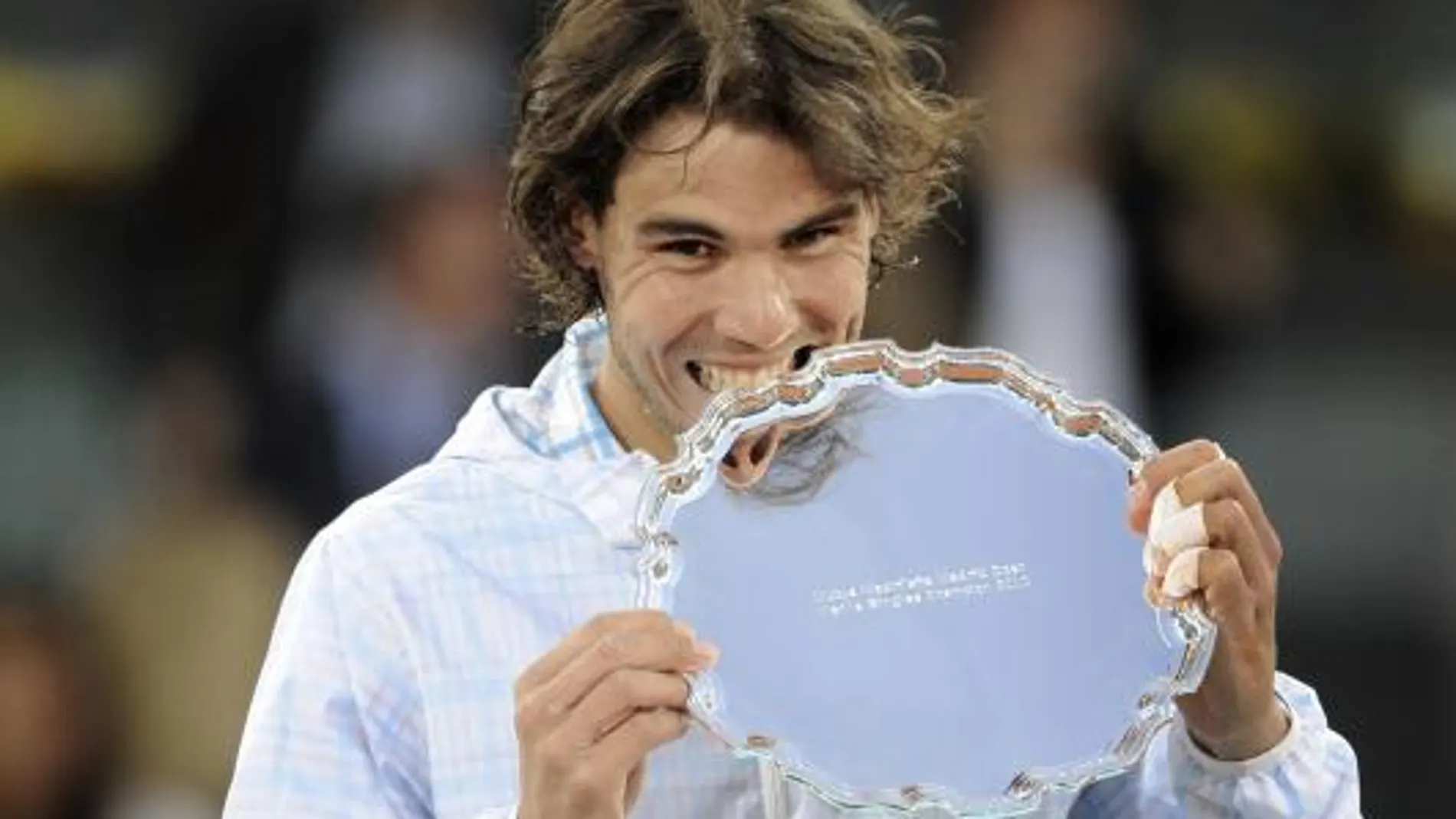 El tenista español Rafa Nadal muerde el trofeo tras ganar al suizo Roger Federer
