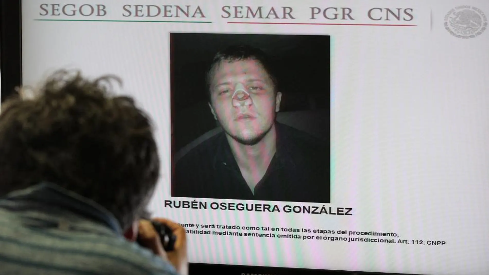 Un fotógrafo toma imágenes hoy, martes 23 de junio de 2015, a una pantalla con el rostro de de Rubén Oseguera González, alias el Menchito, hijo del líder del Cártel Jalisco Nueva Generación (CJNG)