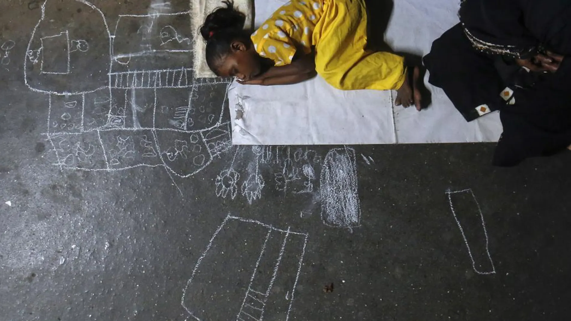 Una niña sin hogar duerme en la estación de trenes de Mumbai, en India, mientras espera que su madre vuelva de mendigar.