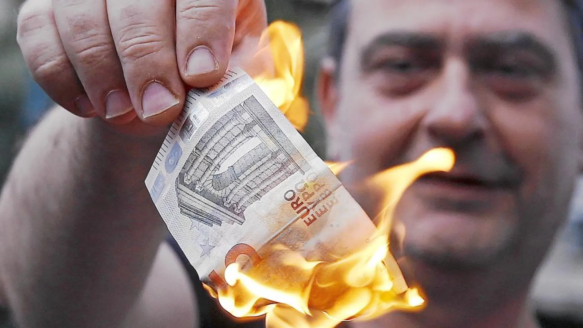 Un hombre prende fuego a un billete de cinco euros como protesta antieuropea