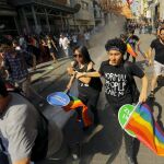 Varios jóvenes con banderas arcoíris huyen de los cañones de agua en Estambul