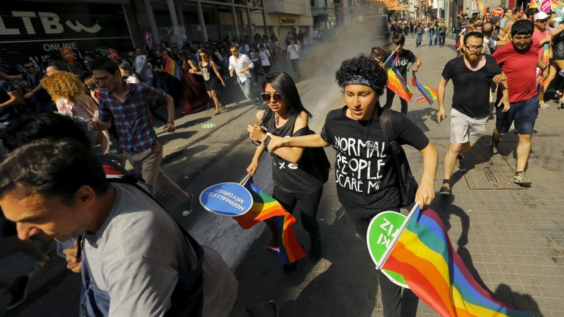 Varios jóvenes con banderas arcoíris huyen de los cañones de agua en Estambul