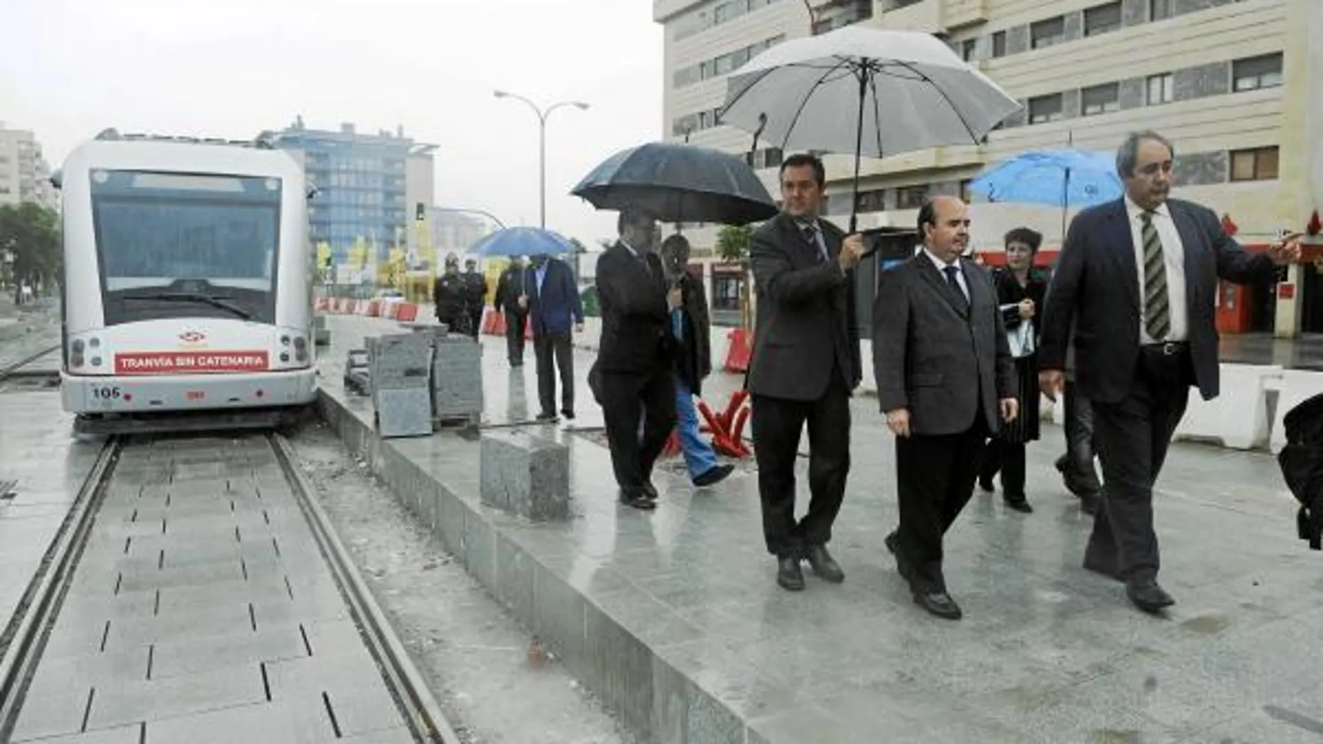 El secretario de Estado, Gaspar Zarrías; el senador Juan Espadas, con paraguas; y el edil de Movilidad, Francisco Fernández, desprotegido