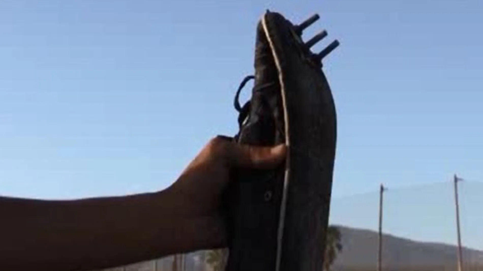 Uno de los subsaharianos enseña las zapatillas con las que ha conseguido saltar la valla