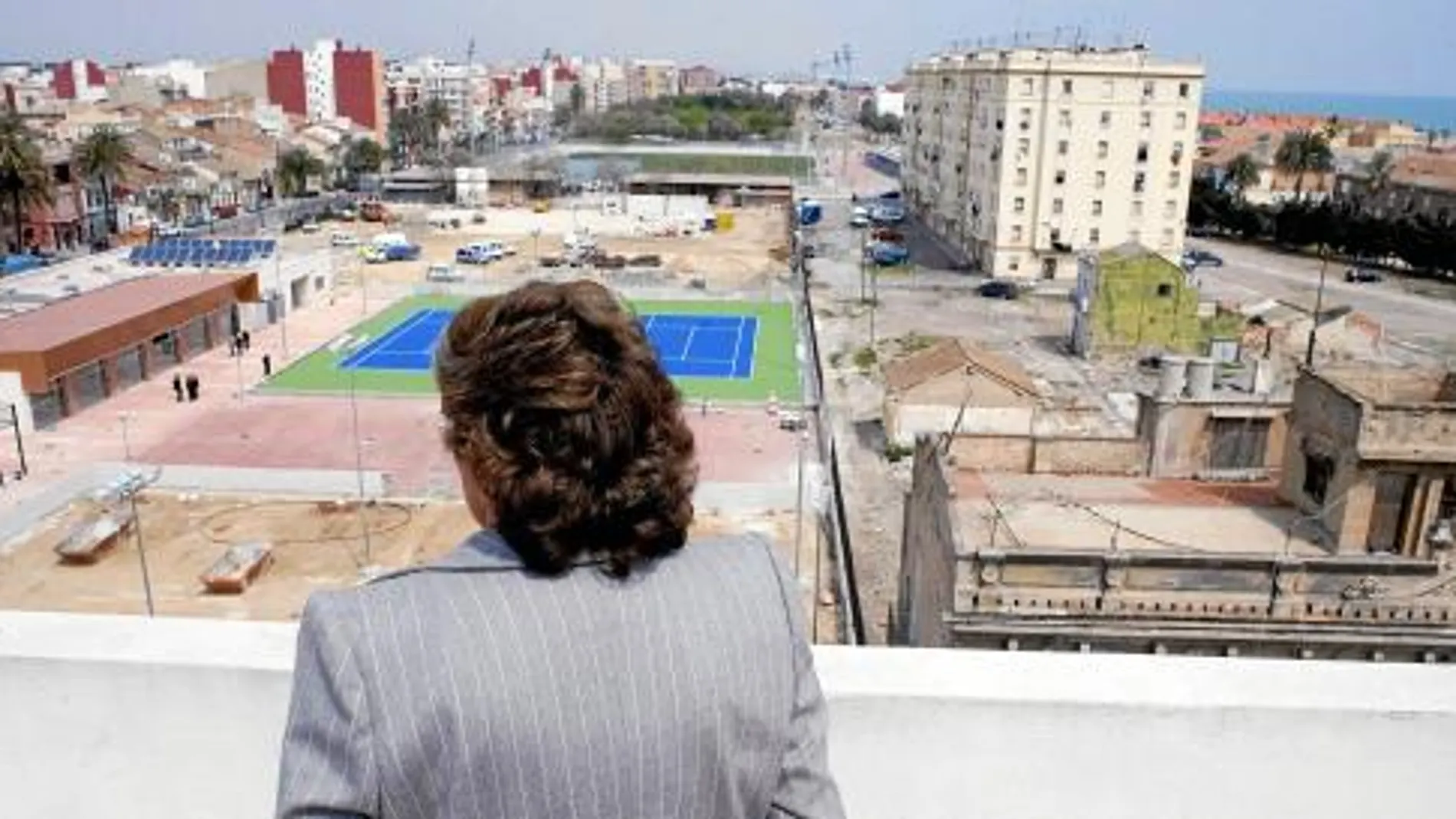 Rita Barberá, en una de sus últimas visitas al barrio. Al fondo a la derecha, el edificio de pescadores