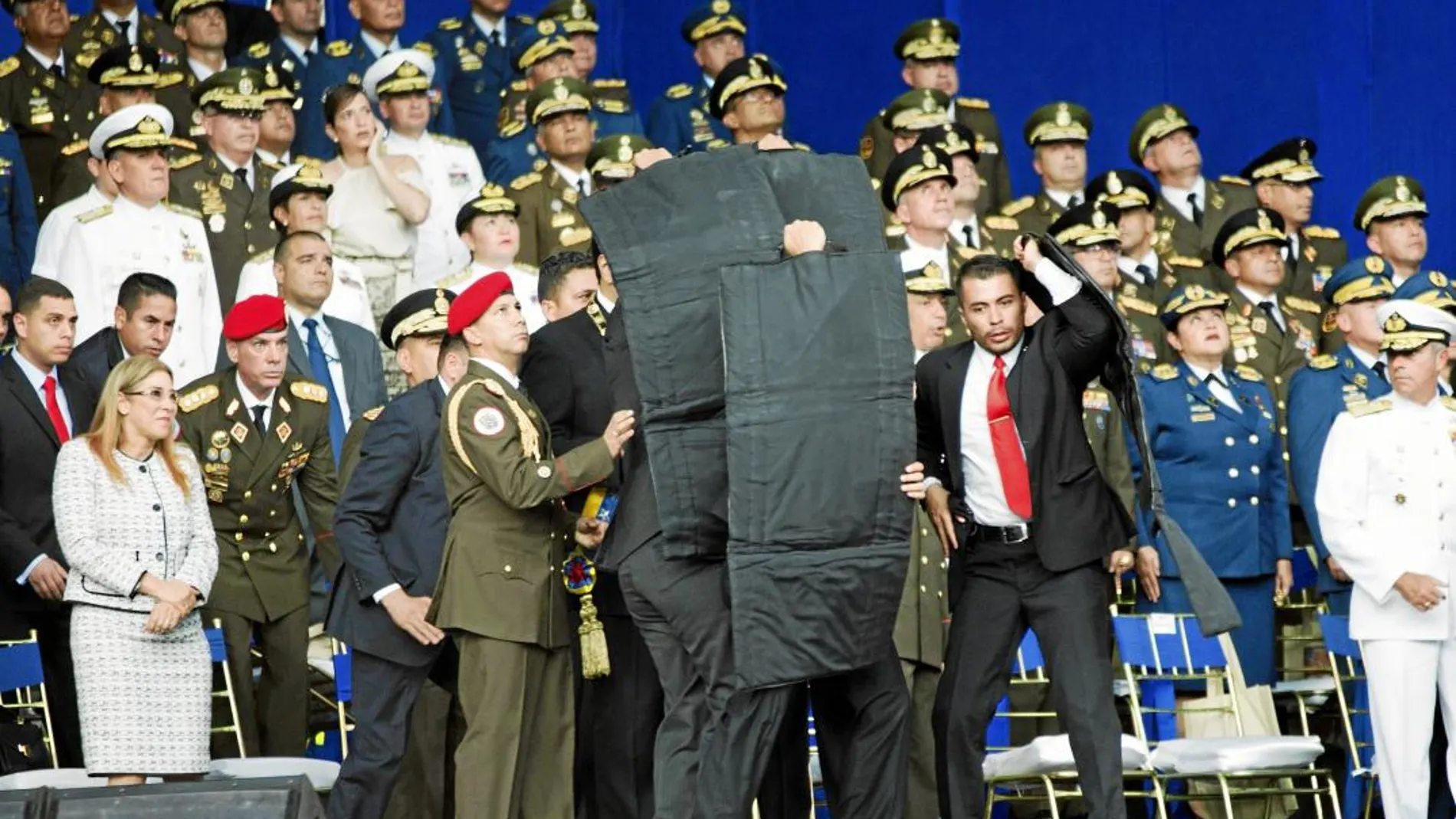 Miembros de la escolta presidencial despliegan un escudo antibalas kevlar capaz de detener la trayectoria de un misil para evitar que Maduro sea alcanzado por los drones / Ap