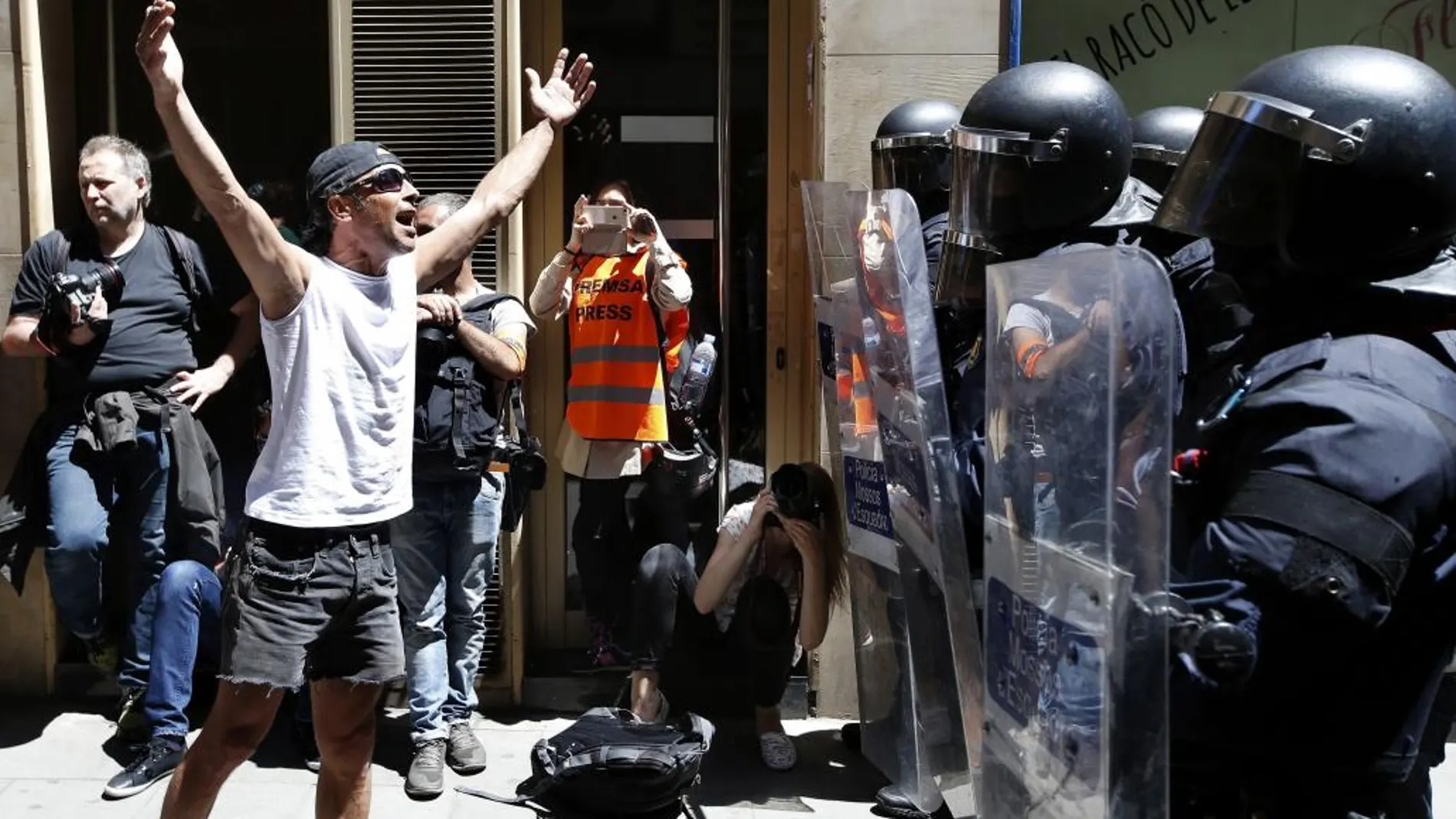 Un manifestante increpa a los antidisturbios de los Mossos d'Esquadra, durante los incidentes producidos hoy en el barrio de Gràcia de Barcelona.