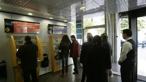 Un grupo de clientes saca dinero del cajero.