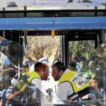 Dos miembros de los equipos de rescate israelí hablan a través del cristal roto de un autobús atacado ayer en Jerusalén