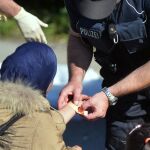 Un policía coloca una pulsera identificativa en el brazo de una mujer a su llegada a Freilassing (Alemania)