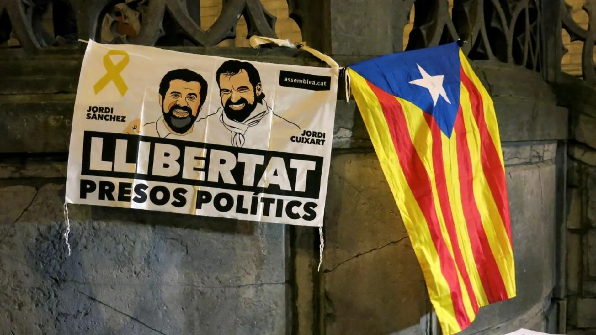 Vista de una pancarta con la imagen de los dirigentes de las entidades independentistas Jordi Sànchez y Jordi Cuixart que se encuentran en prisión, y una estelada durante una concentración organizada por la ANC