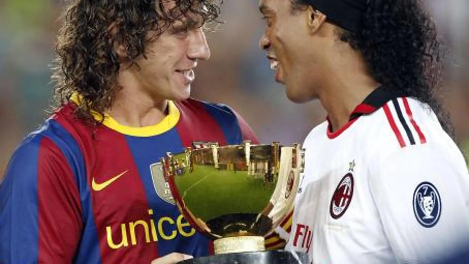 El capitán del FC Barcelona, Carles Puyol (i) entrega el trofeo conseguido al delantero brasileño del AC. Milan, Ronaldinho Gaucho, tras el partido, correspondiente a la edición 45 del trofeo Joan Gamper