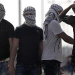 Palestinos con la cara cubierta se enfrentan a fuerzas israelíes durante enfrentamientos en Erez, entre Israel y la Franja de Gaza