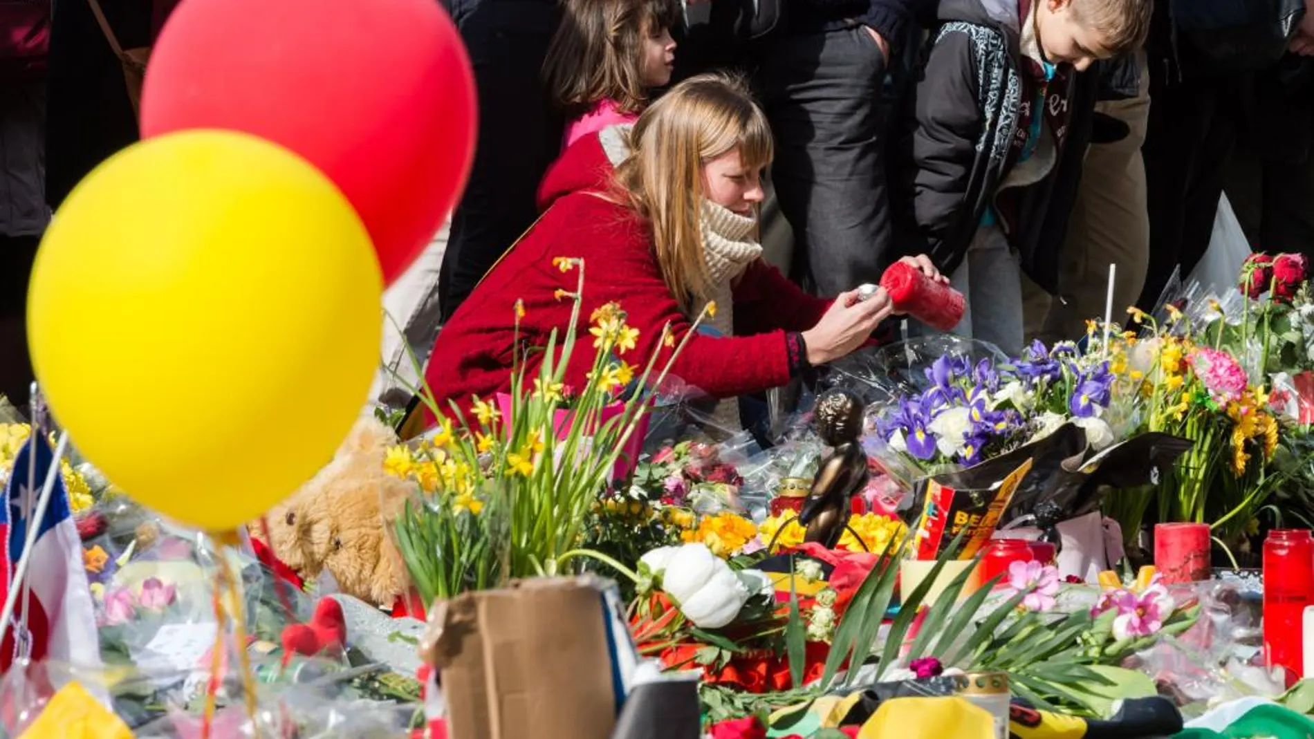 Una mujer enciende una vela en recuerdo de las víctimas en la Plaza de la Bolsa de Bruselas