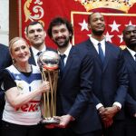 La presidenta de la Comunidad de Madrid, Cristina Cifuentes (2i), junto al base Sergio Llull (3d) y los jugadores Ayón, Maciulis, Randolph y Othello Hunter (i-d), posa para la foto de familia con el trofeo durante el homenaje que han recibido los jugadores del Real Madrid de baloncesto en la sede de la Comunidad