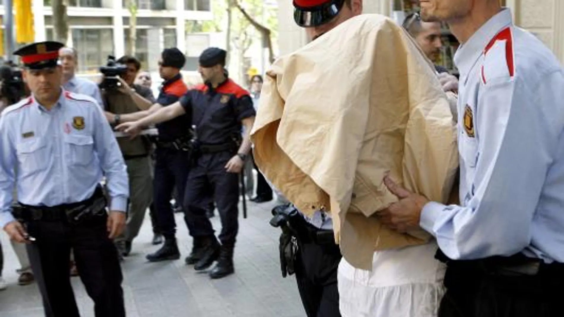 Lianne Ross Smith, con el rostro cubierto, es escoltada por dos mossos al salir del piso de Barcelona donde vivía con su pareja y los niños fallecidos