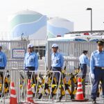 Agentes de policía y guardas de seguridad frente a la verja de entrada de los reactores 2 y 3 de Fukushima