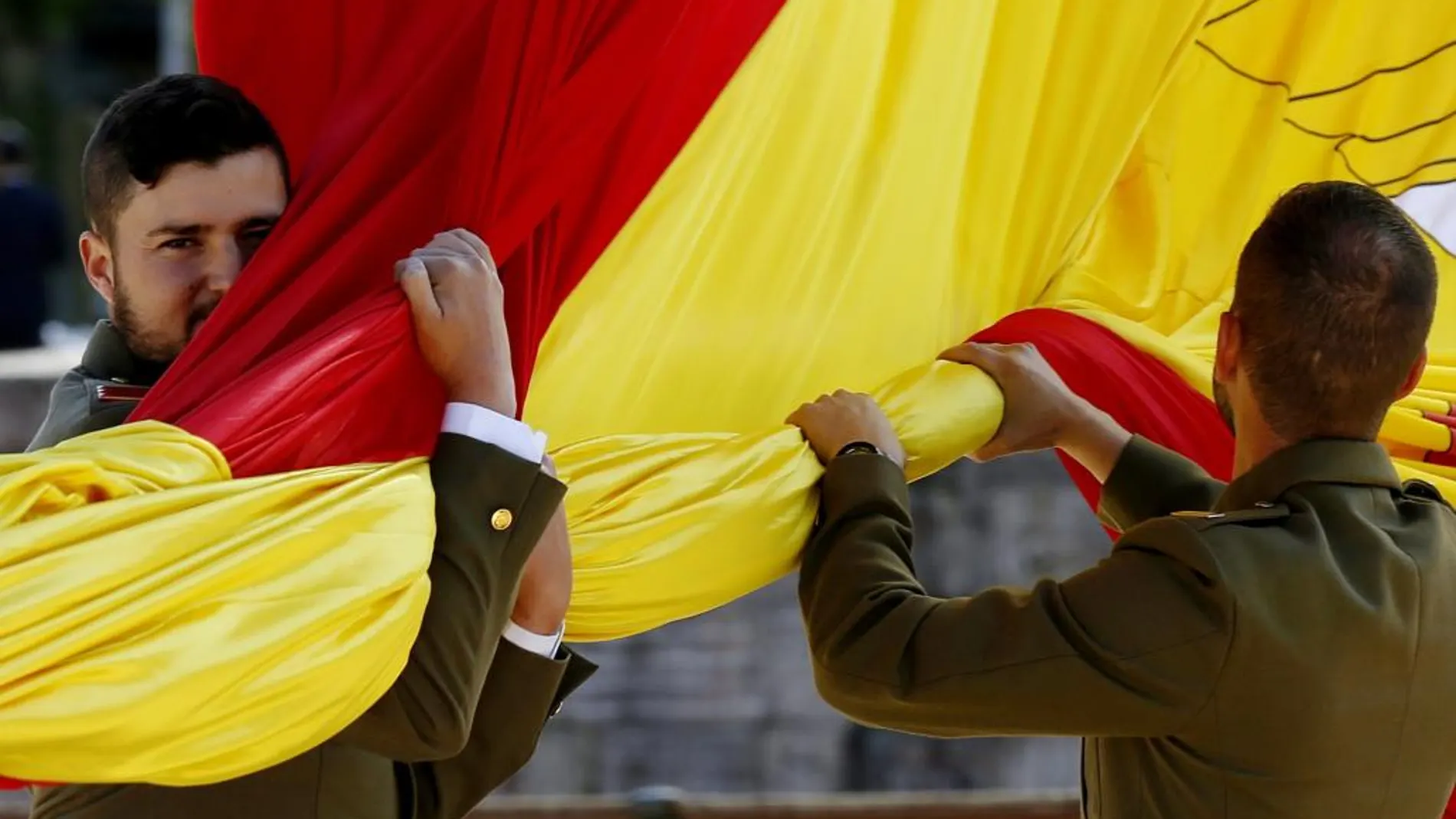 Dos soldados del Ejército de Tierra proceden al Izado de la Bandera en la Plaza de Colón de Madrid con motivo del Día de las Fuerzas Armadas