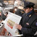 Un policía lee «L'Osservartore Romano» en un quiosco en Roma