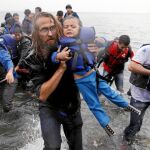 Un voluntario de una ONG atiende a un menor recién llegado a la isla griega de Lesbos procedente de Turquía