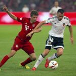 El valencianista Javi Fuego trata de retener el balón ante Thomas Mueller, del Bayern de Múnich, en el amistoso de Beijing