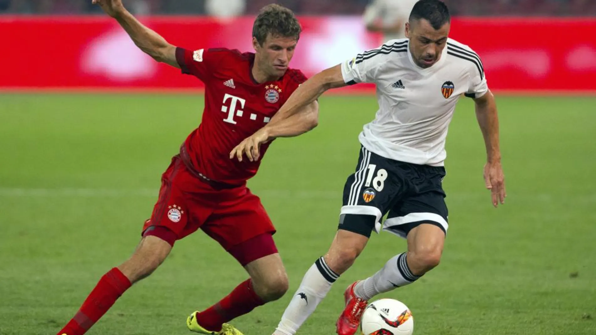 El valencianista Javi Fuego trata de retener el balón ante Thomas Mueller, del Bayern de Múnich, en el amistoso de Beijing