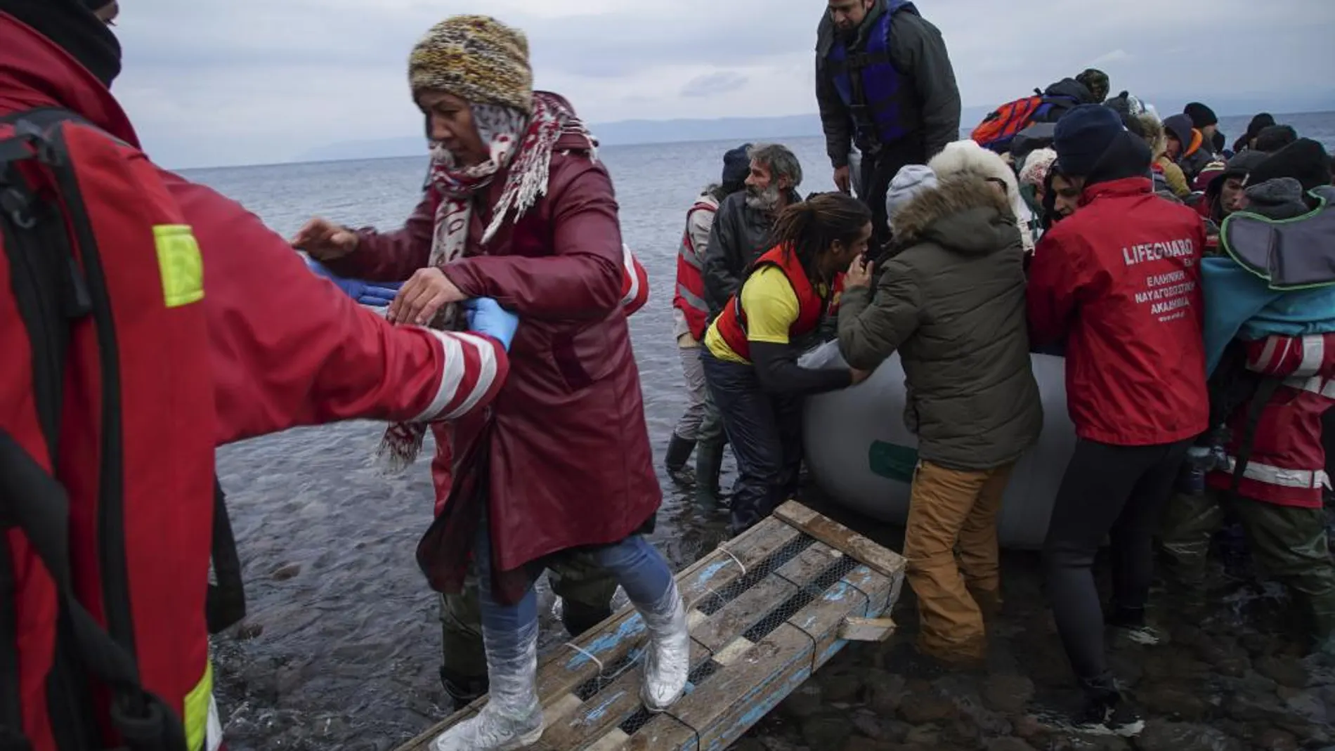 Los voluntarios ayudan a grupo de refugiados llegados a las costas griegas desde Turquía.