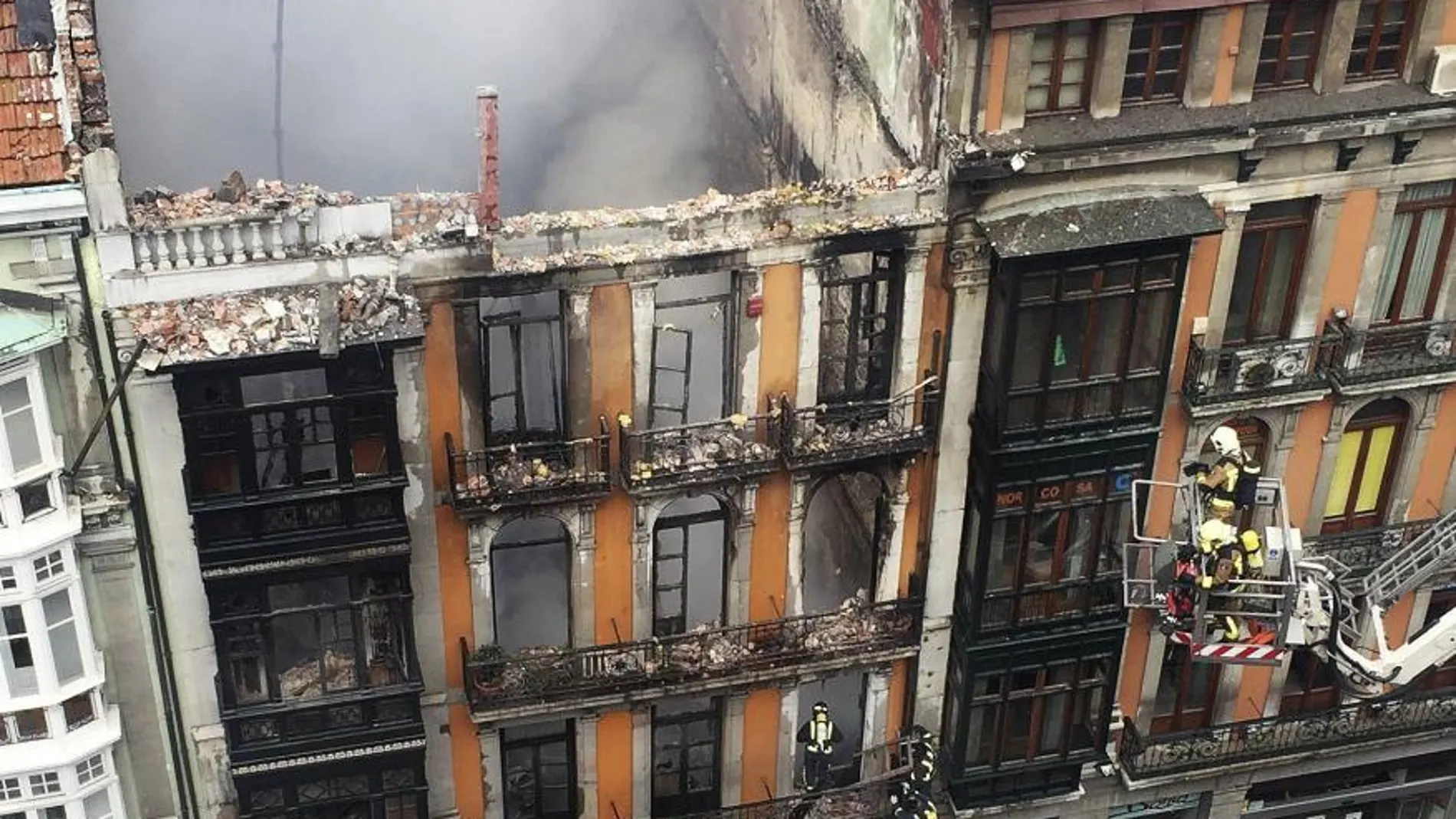 Un grupo de bomberos trata de entrar para rescate el cuerpo del compañero fallecido.