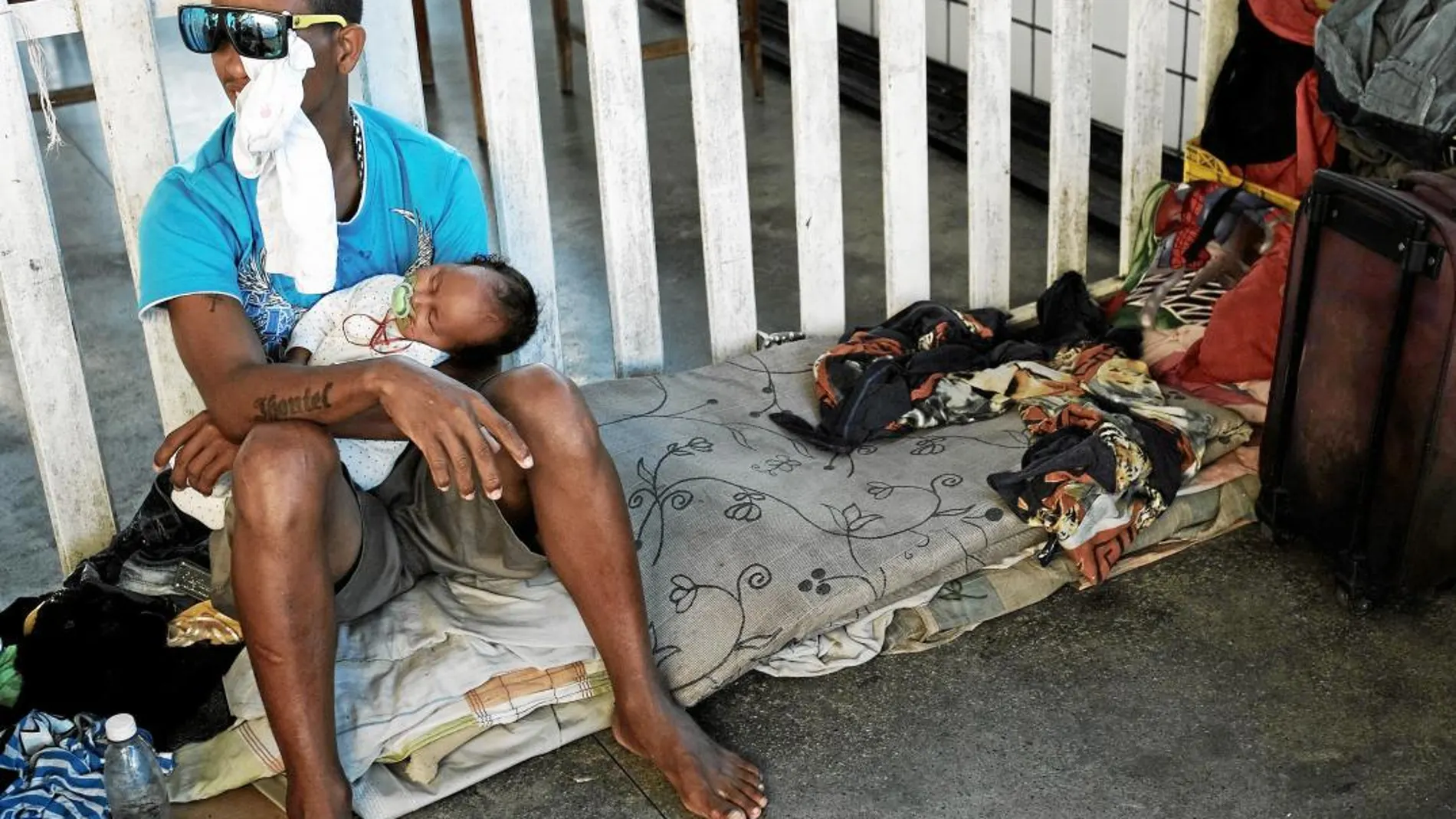 Un venezolano, aquejado de una grave conjuntivitis, sostiene a su hijo en brazos en el control fronterizo de Pacaraima con Brasil