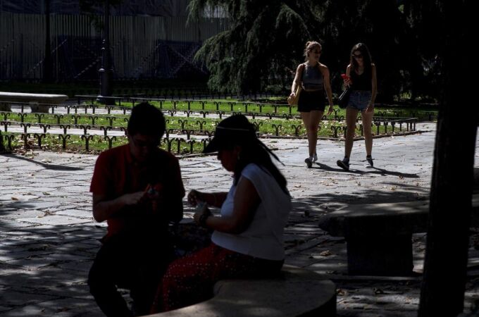 Varios turistas se protegen del sol durante la ola de calor en el madrileño parque de El Retiro / Foto: Efe