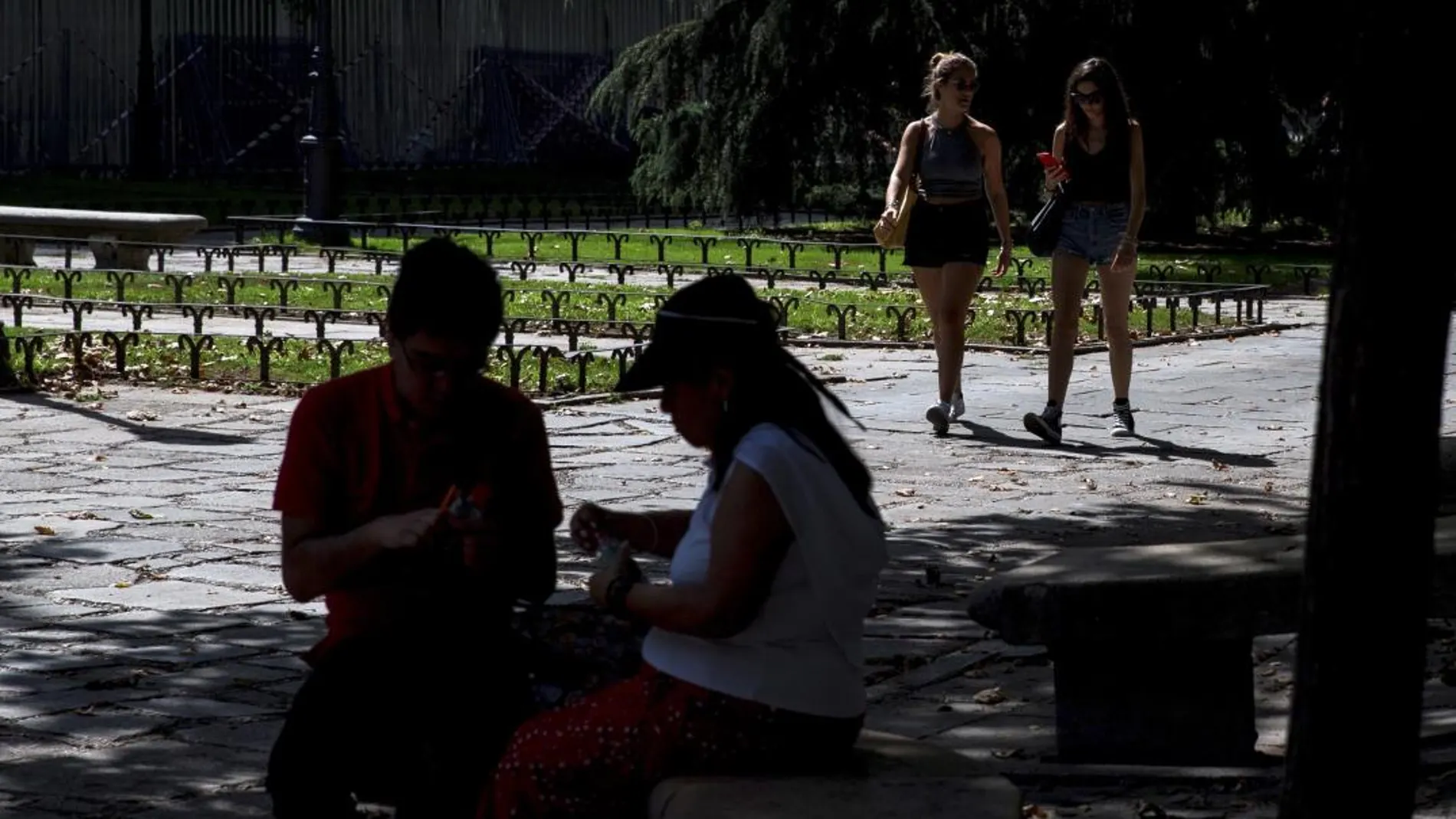 Varios turistas se protegen del sol durante la ola de calor en el madrileño parque de El Retiro / Foto: Efe