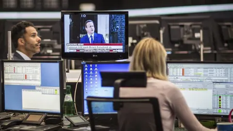 Una mujer observa la evolución del DAX 30 mientras escucha la comparecencia de David Cameron, en el parqué de Fráncfort (Alemania).