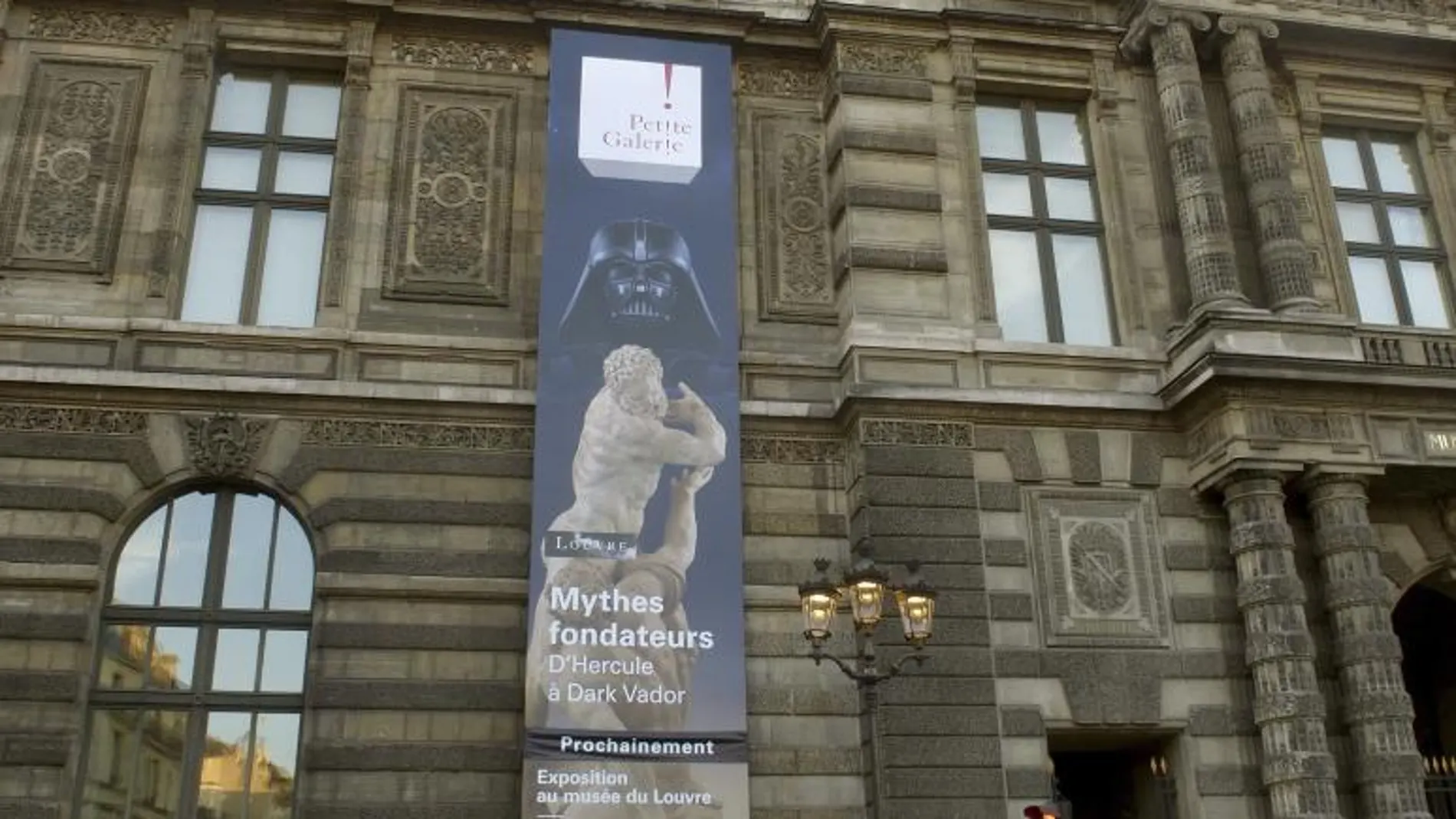 Fachada del Louvre en la calle Rivoli, donde se anuncia la exposición "Mitos fundadores: De Hércules a Darth Vader"