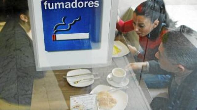Varias personas toman el desayuno en un habitáculo de un bar diseñado para la gente fumadora