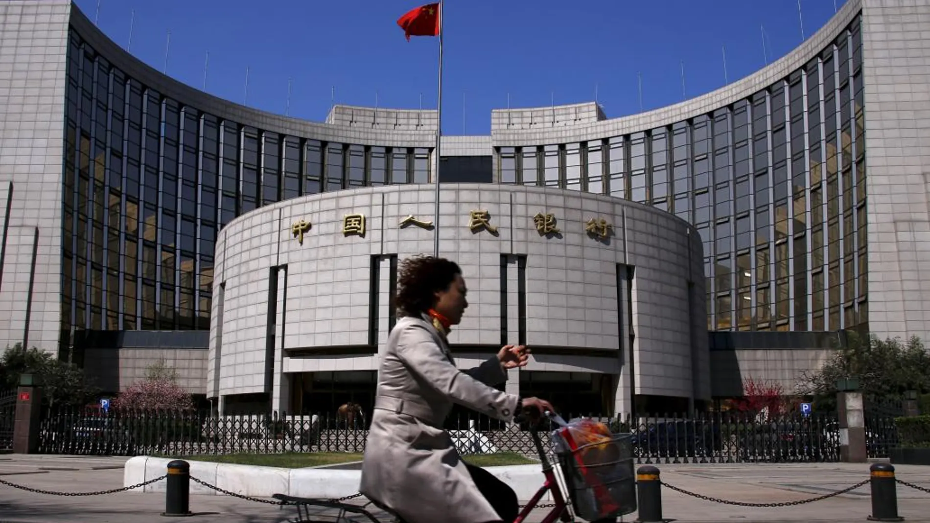 Una mujer pasa por delante del Banco Popular de China en Pekín