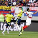 James Rodriguez, de Colombia, remata de cabeza ante el jugador de Perú, Joel Sanchez