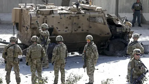 Soldados de la OTAN junto a uno de sus vehículos militares dañados por un coche bomba en Kabul, ayer