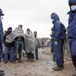Varios inmigrantes esperan las órdenes de los guardias croatas tras su llegada al campamento de Opatovac