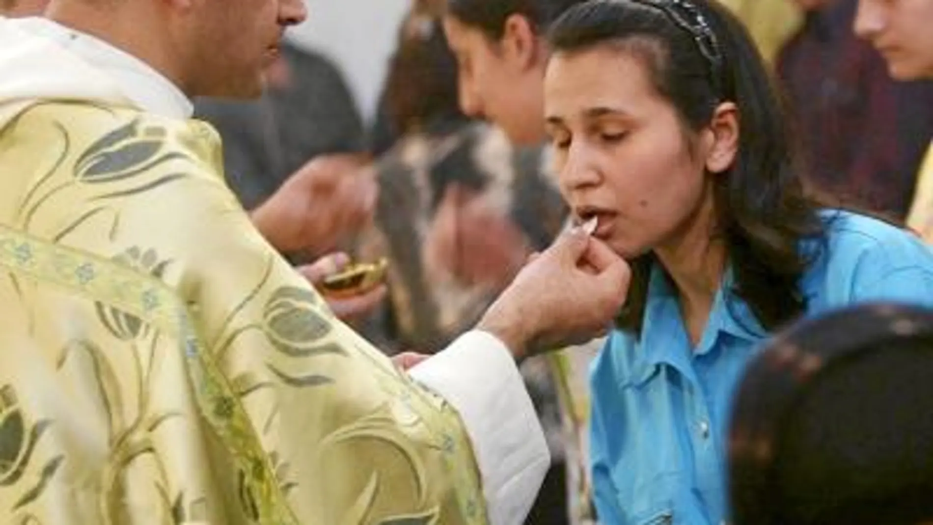 Una católica iraquí acude a comulgar en una parroquia de Bagdad, donde todas las celebraciones navideñas serán diurnas