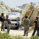 Soldados israelíes inspeccionan un automóvil calcinado en el lugar donde fue emboscada una patrulla policial, cerca de la ciudad cisjordana de Hebrón